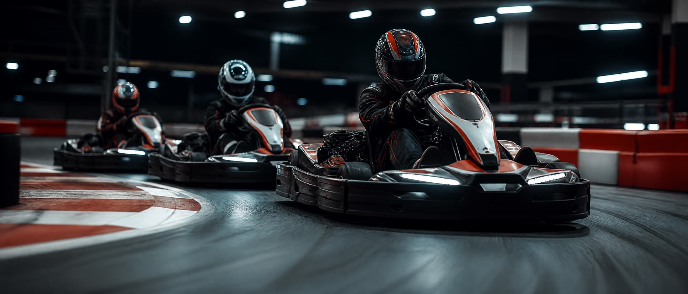 Three go-karts racing into a corner on an indoor track